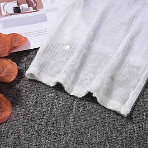 Détail du tissu en maille blanche avec broderie de paillettes verticales pour pantalon