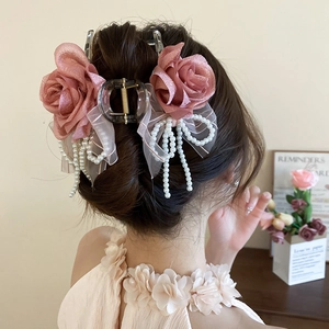 Dettaglio molletta per capelli con rose di raso rosa, fiocco di perle e nappine pendenti