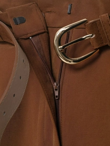 Détail d'un pantalon marron avec fermeture éclair en métal et ceinture à boucle dorée