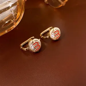 Golden earrings with red number 3 and zircon stones on premium brown leather background