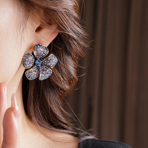 Gros plan de boucles d'oreilles fleur vintage avec cristaux bleus et violets sur modèle