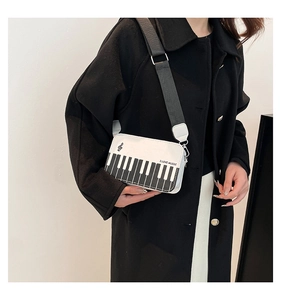 Detail of white crossbody bag featuring black piano key pattern and I LOVE MUSIC text