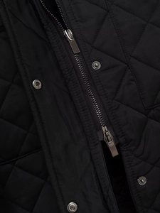 Detail einer schwarzen Steppjacke mit Rautenmuster und hochwertigen Metallreißverschlüssen