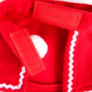 Close-up of red fleece pet cloak with white wavy trim and adjustable velcro fastener