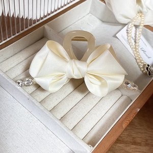 Detail of cream satin ribbon hair claw clip with rhinestones on a jewelry box