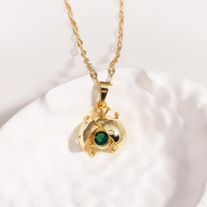 Detail of gold ladybug pendant with green crystals and small diamonds on a chain