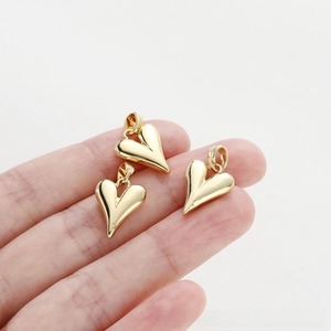 Macro view of three gold heart pendants held by hand for jewelry making and necklaces