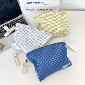 Detail of plaid cosmetic bags showing zipper closure and fabric texture in office setting