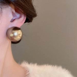 Vue macro d'une grande boucle d'oreille sphérique or champagne finition miroir sur mannequin