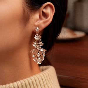 Detailed close-up of champagne crystal feather tassel earrings worn by a model