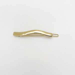 Polished gold wavy metal hair clip detail with minimalist irregular spring clamp design