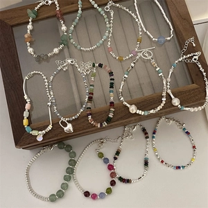 Detail of beaded bracelets featuring natural stones, pearls, and silver heart pendants