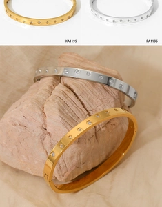 Close-up of gold and silver stainless steel bangles with cubic zirconia on natural stone