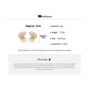 Vue détaillée de grandes boucles d'oreilles fleurs ajourées dorées de 7cm par 5cm