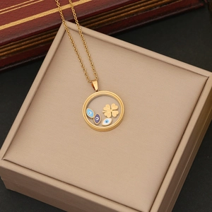 Detail of gold evil eye pendant necklace with movable clover charms on a jewelry box