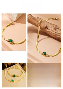 Close-up of vintage emerald green oval gemstone on golden snake chain necklace and bracelet set