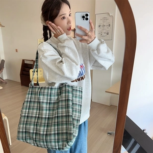 Lifestyle shot of large green plaid canvas tote bag worn by a model in a mirror selfie