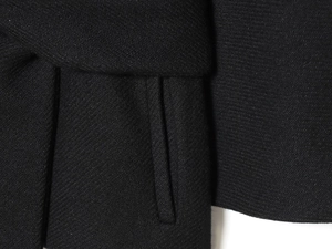 Detailed macro view showing the houndstooth embroidery and fine stitching of the black jacket