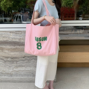 Detail of pink canvas tote bag with MAISON 8 print on neutral stone background