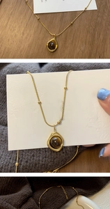 Detailed view of vintage gold necklace with brown tiger eye pendant on knit fabric