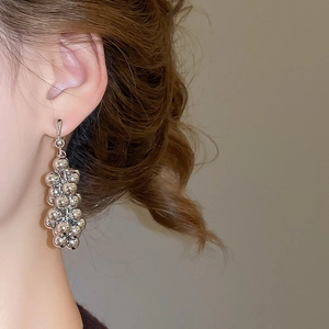 Détail de boucles d'oreilles pendantes géométriques argentées à plusieurs sphères