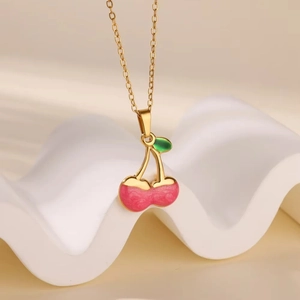 Detailed view of cherry pendant necklace with pink enamel and gold-plated chain links