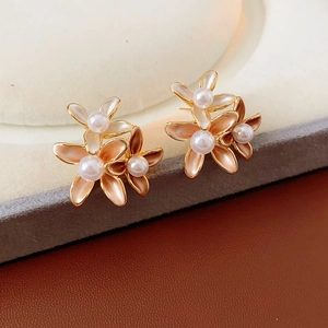 Macro detail of gold-plated floral earrings with pearls and champagne enamel petals