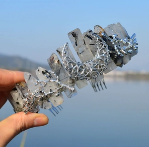 Detailed view of silver crescent moon and branch charms on raw crystal crown headband