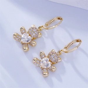 Close-up of golden bear earrings with paved white zircons and a heart-shaped center stone