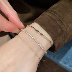 Macro shot of gold-plated snake chain and zircon tennis bracelet set on wrist
