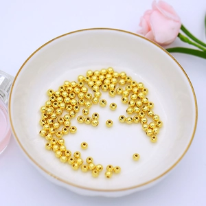 Detailed macro view of 18K gold plated spherical spacer beads in a white porcelain bowl