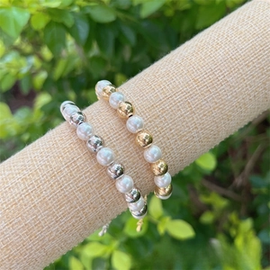 Detail of 18K gold and silver plated beaded bracelets with white faux pearls and chain