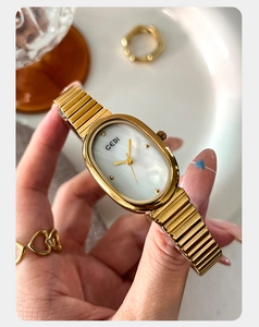Close-up of golden oval watch with mother-of-pearl dial and metallic stretch band