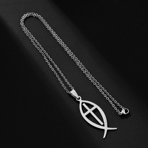 Close-up of silver hollow fish pendant necklace with cross design on dark background