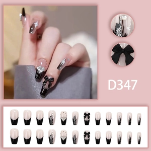 Detail of elegant black French press-on nails with 3D bow and sparkling heart rhinestone
