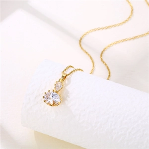 Gold stainless steel necklace with oval and pear cut crystal pendant on a textured stand