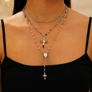 Close-up of layered cross necklace with colorful beads and charms on a model