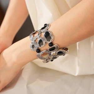 Macro detail of wide vintage silver cuff bracelet with black stones on a soft fabric