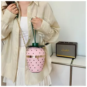 Détail du sac seau fraise rose avec bandoulière chaîne en métal et décor de feuilles