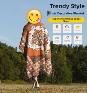 Detail of bohemian outdoor blanket featuring orange geometric patterns and tassel edges