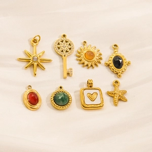 Eight gold-plated assorted pendant charms with gems and pearls on white cloth