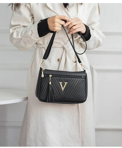 Detail view of a stylish black crossbody bag with tassel and gold V hardware accent.