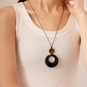 Detail shot of the black resin hoop and dark wood disc on a long sweater chain