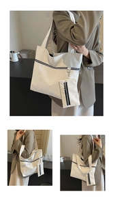 Detail view of white tote bag with textured faux leather and black zipper pocket accent