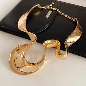 Close-up of golden irregular wavy geometric collar necklace with adjustable clasp detail