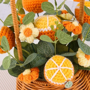 Handmade crochet flower bouquet in a woven basket with orange fruit slices and green leaves