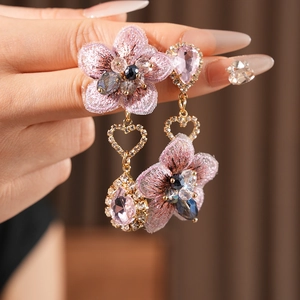 Close-up of vintage pink fabric flower earrings with teardrop gems and heart metal detail