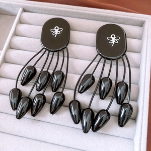 Détail de boucles d'oreilles ethniques à pompons avec papillon argenté sur fond noir