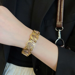 Detail of vintage gold religious bracelet featuring embossed crosses and fish symbols