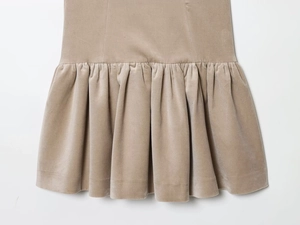 Détail de l'ourlet plissé d'une jupe en velours beige montrant la texture douce